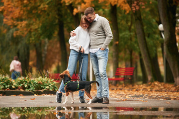 Autumn season walk. Lovely couple are with their cute dog outdoors