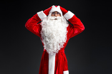 Portrait of funny scared Santa Claus holding head looking at camera isolated on black backgriund