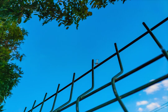 Metal fence blocks access to the blurred plane flying away from us. Concept of abstract boundaries imposed on us by the system, restrictions on the rights to freedom, movement, and free thought
