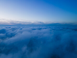 Fototapeta premium A drone flies over fluffy clouds at sunset. The drone flies through the clouds, creating a sense of wonder and awe