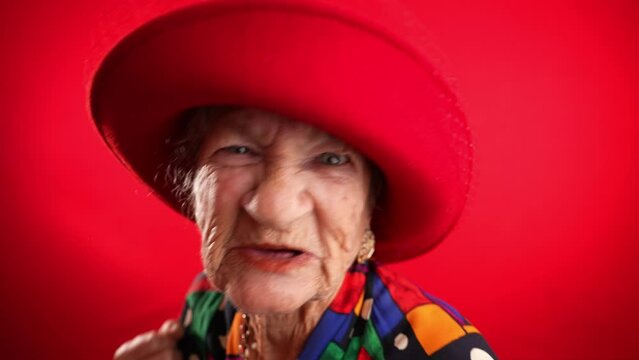 Funny portrait of elderly mature angry aggressive woman trying to fight towards camera, shaking fist, boxing.