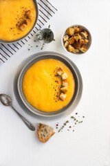 Pumpkin soup served with croutons, on white textured background.. Healthy food, slow cooking. Top view. Copy space.