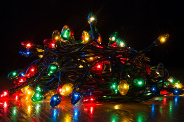 Fototapeta na wymiar Christmas lights with a reflection on a black background