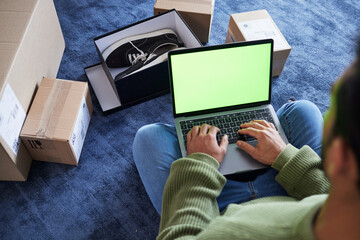 Online shopping, man with laptop, green screen and package on floor, shoes and delivery service on digital app. Sale, discount and ecommerce on fashion retail website, internet search on computer.