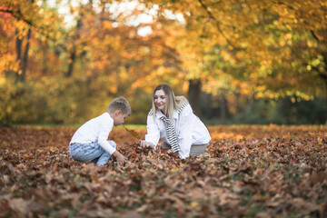 Happy young mother and two brothers walking in the autumn forest. Autumn outdoor activity for...