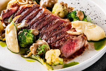 Cooked sliced beef steak rare with green broccoli.