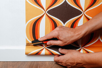 man cutting the edges of the wallpaper