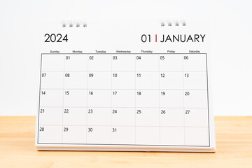Monthly desk calendar January 2024 year on wooden table.