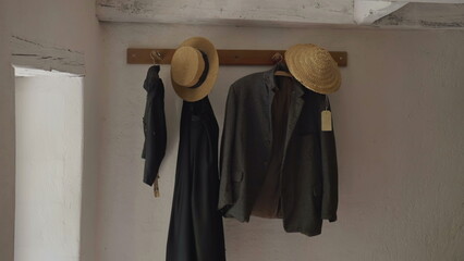 Farmhouse suit with hats hanging by door. Traditional ancient Swiss clothing at rural setting, historic fashion clothes