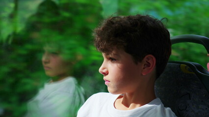 close-up of contemplative preteen boy aboard bus, engrossed in scenic journey through window. Young...