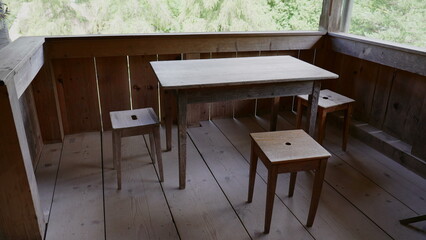 Rustic rural wooden balcony with aged table and chairs in farmhouse setting