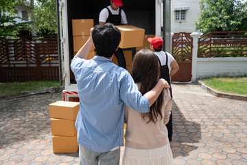 Asia couple checking cardboard box with caucasian delivery man carrying cardboard box at new home