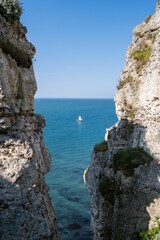 Fototapeta premium Sailboat is sailing in the ocean with cliffs in the foreground