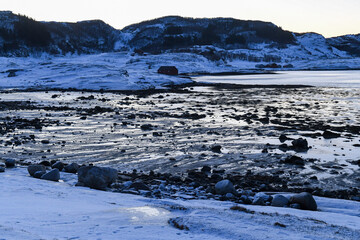 Wide angle landscape shot of the snow covered mountains and beach near Mjelle, part of the Bodo community in Arctic Norway, during the brief period of daylight in the arctic winter.