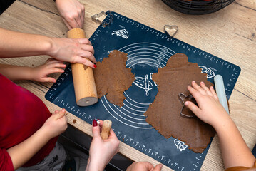 Children make gingerbread dough using a wooden and plastic rolling pin.