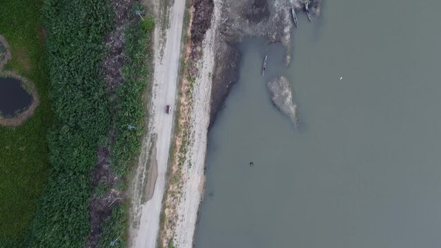 Aerial view of bentor (becak motor) riders speeding on the road across Lake Limboto. aerial view of a lake experiencing drought