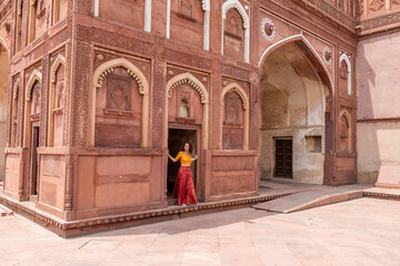 Woman walks through the great Agra Fort in Agra, India, with its wonderful architecture on a cloudy day - obrazy, fototapety, plakaty