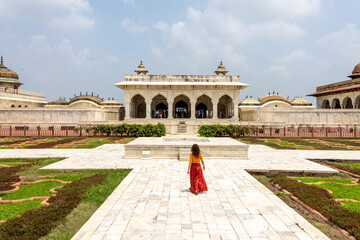 Woman walks through the great Agra Fort in Agra, India, with its wonderful architecture on a cloudy day