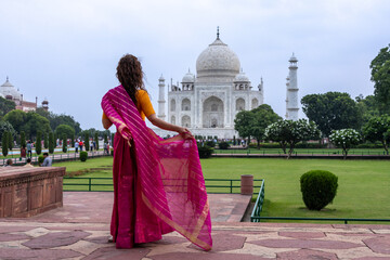 Woman looks at the imposing Taj Mahal in Agra, India, with its wonderful architecture on a cloudy day