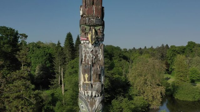 Raising drone footage showing a wooden totem ith vegetation trees in the background