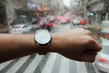 A man's point of view as he checks time on his watch. In the background, a rain-drop window and...