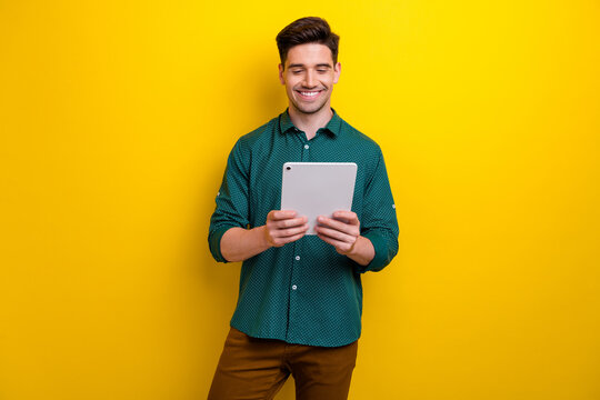 Photo of cheerful nice man hand hold apple ipad gadget writing reading news social media isolated on yellow color background
