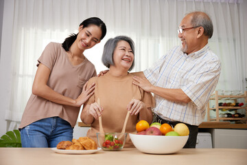 asian family senior couple and granddaughter enjoy cooking salad in the kitchen