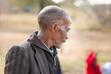portrait of an unshaved old african man in the village,late afternoon