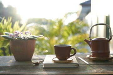Brown tea cup and tea pot with brown plant pot and notebooks