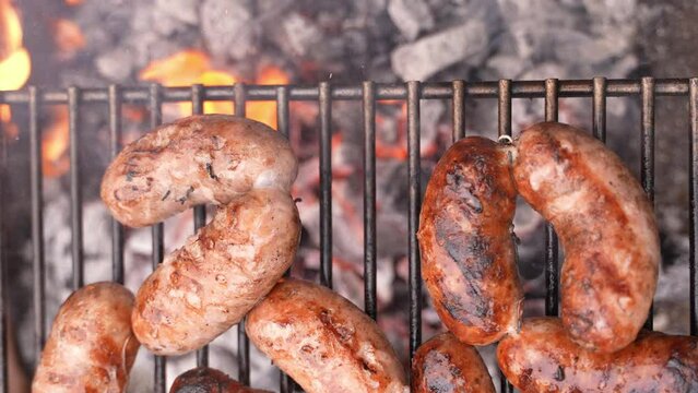 Flatlay overhead shot of cooking sizzling sausages BBQ using a fork on a grill. Barbecue.