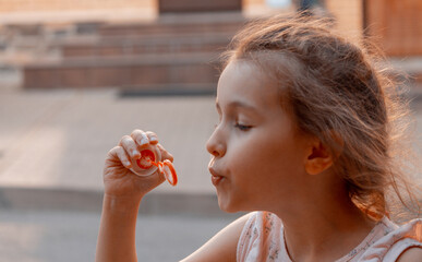 A little girl with red or brown hair blows soap bubbles. The concept of a carefree, happy, peaceful...