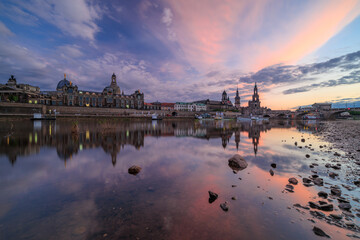 Sunset in front of the skyline of Dresden on the Elbe,
photographed in a low perspective with reflection in the water - obrazy, fototapety, plakaty
