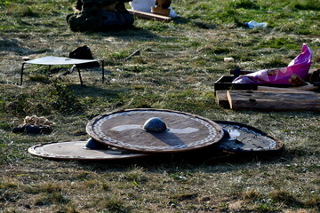 A close up on a remnants of viking or medieval temporary camp, including wooden chests, tools, shields, targes, weapons, tents, armour, helmets, chainmails, and lanterns seen in summer in Poland