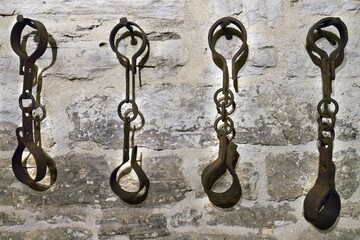 four pieces of iron and hooks hanging up to a brick wall