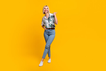 Fototapeta na wymiar Full length photo of charming pretty woman dressed print shirt looking showing thumb empty space isolated yellow color background