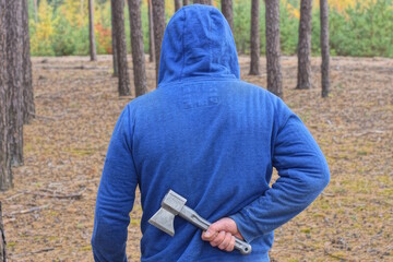 one man in blue clothes hides his hand with a gray ax behind his back on the street