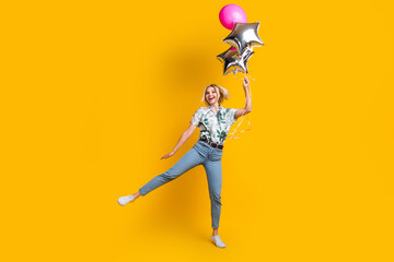 Fototapeta na wymiar Full length photo of overjoyed girl dressed print shirt jumping hold bubbles celebrate anniversary isolated on yellow color background