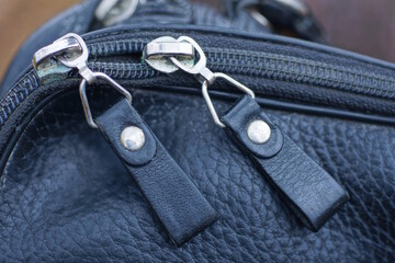 two white metal zips on the black leather of an old bag