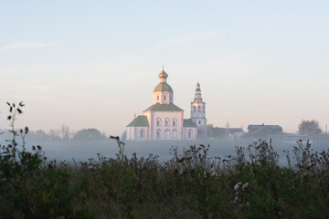 Fototapeta na wymiar autumn landscape with soft morning light, church at dawn in the fog. Suzdal, Russia