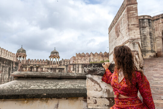 Woman dressed in red walking through Mehrangarh Fort in Jodhpur in Rajasthan, India. Known as the blue city