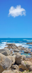 Boulders at a beach shore with majestic ocean across the horizon. Copyspace at sea with blue sky background and rocky coast in Camps Bay, South Africa. Calm and scenic landscape for a summer holiday