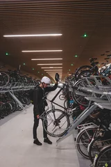 Fotobehang Traveller is surprised by the huge underground cycle station under the main overpass in Amsterdam, Netherlands. Inserting the wheel into the attachment and bike handle © Fauren