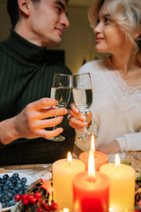 Vertical portrait of loving young couple clinking glass of champagne on valentine's day. Happy romance new marriage man and woman having dinner night party to celebrate wedding anniversary together.