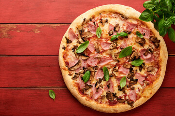 Pizza. Traditional Bacon pizza with ham, mushrooms, pickled cucumber and cheese and cooking ingredients tomatoes basil on wooden table backgrounds. Italian Traditional food. Top view. Mock up.