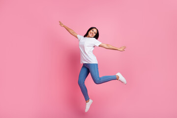 Fototapeta na wymiar Full body size photo of carefree young woman flying jump trampoline wings arms enjoying traveling isolated on pink color background