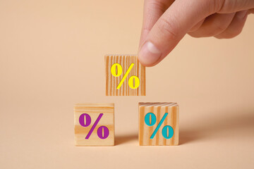 Woman arranging cubes with percent signs on beige background, closeup