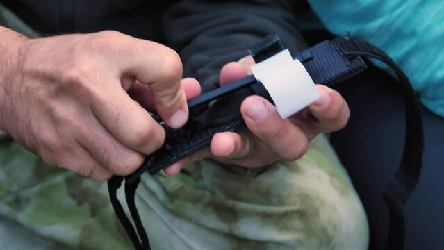 In the hands of a man military tourniquet to stop blood. Close-up. A military instructor is telling how to use the tourniquet. Training on the courses of medical aid in wounding