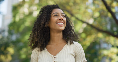 Young black woman smiling happy face at a park looking at sky