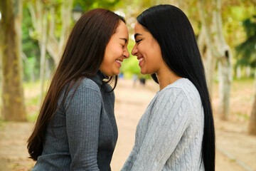 Happy Latin lesbian couple laughing in a park. LGBT couple.