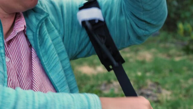 The woman applies a tourniquet to her arm as part of her first aid training. Use of a medical tourniquet to stop bleeding. Close-up. Practicing tactical medicine